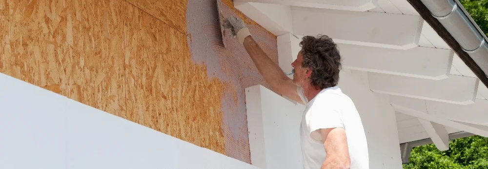 Person verputzt Hauswand mit Kelle